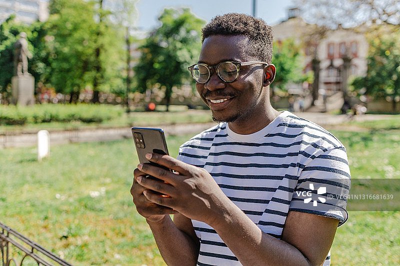 非裔美国年轻人正在公园里使用手机图片素材