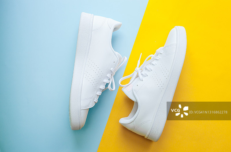 蓝色和黄色背景的白色运动鞋，运动和休闲服装90年代的风格概念。图片素材