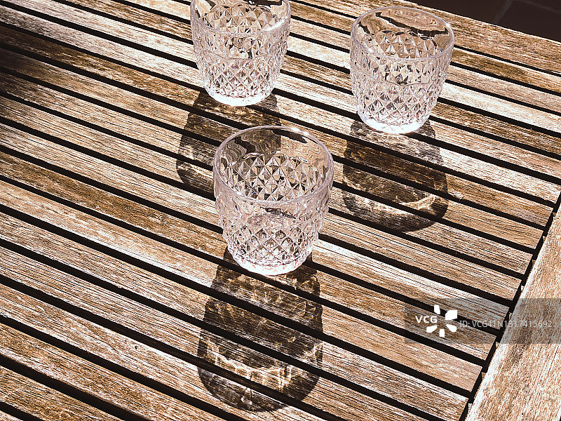 在阳光明媚的日子里，从上面的木头表面上排列着红酒酒杯图片素材