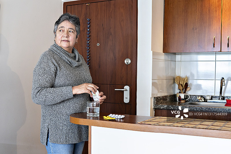 一个在家里吃药的拉丁老妇人图片素材