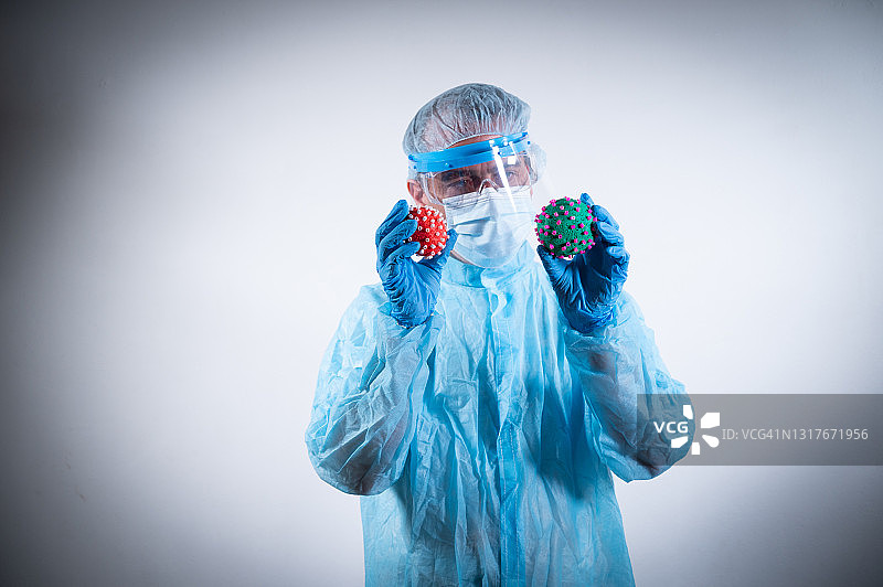 身穿防护服的科学家在他的手中发现了两种不同颜色的冠状病毒图片素材