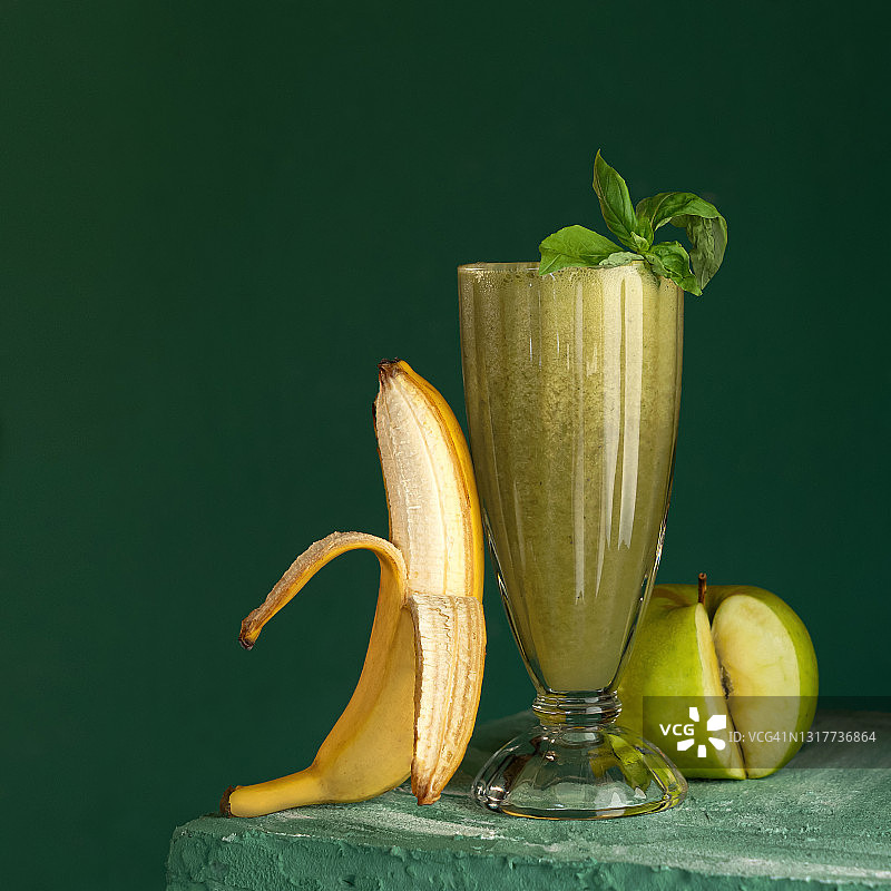 香蕉，苹果和薄荷奶昔。膳食维生素鸡尾酒排毒。玻璃与混合水果在绿色背景。健康的新鲜果汁或软饮料。有机抗氧化产品。本空间图片素材