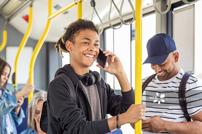 微笑的男孩在公交车上用智能手机图片素材
