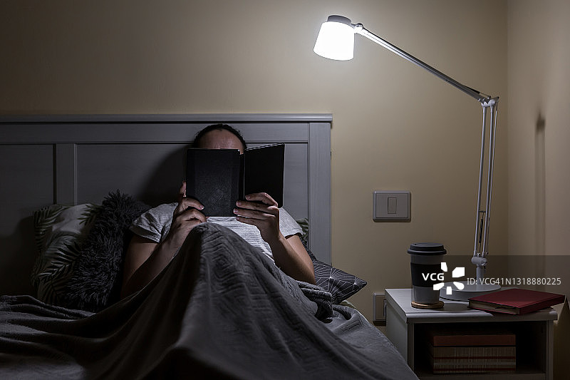 一个无名女子在床上看书图片素材