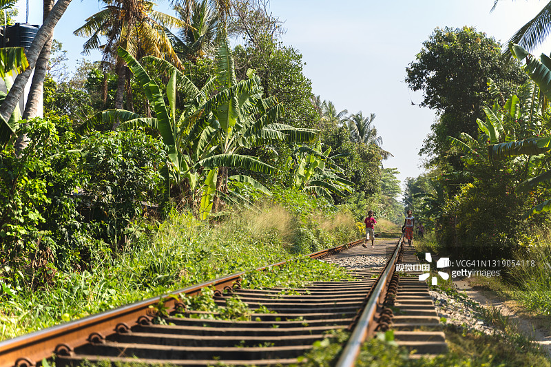 铁路穿过斯里兰卡的丛林。小男孩和小女孩在散步图片素材