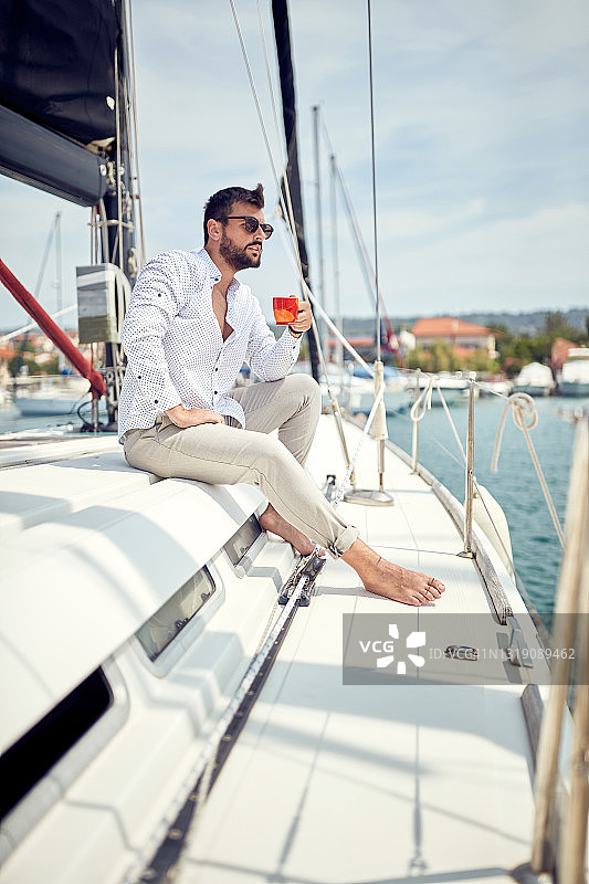一个年轻人坐在海上的游艇上，享受着咖啡。夏天,大海,假期图片素材