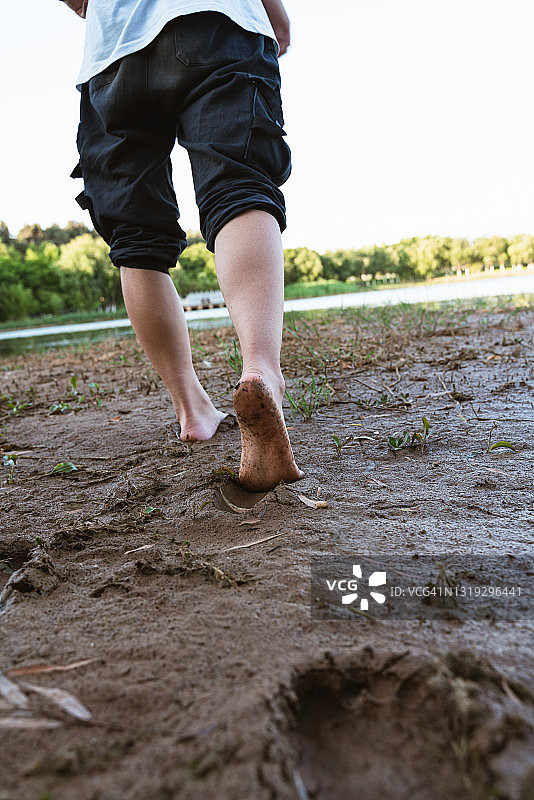 一个亚洲男孩走在泥泞的路上图片素材