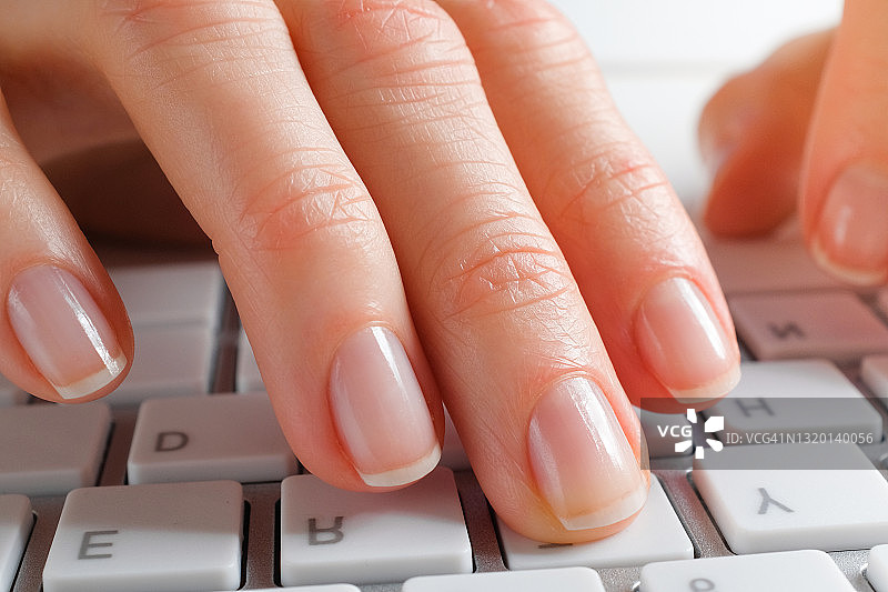 女人的手在电脑或笔记本电脑的键盘上打字。一个办公室职员坐在他的办公桌前。商业、自由职业、在家工作的概念。特写镜头。图片素材