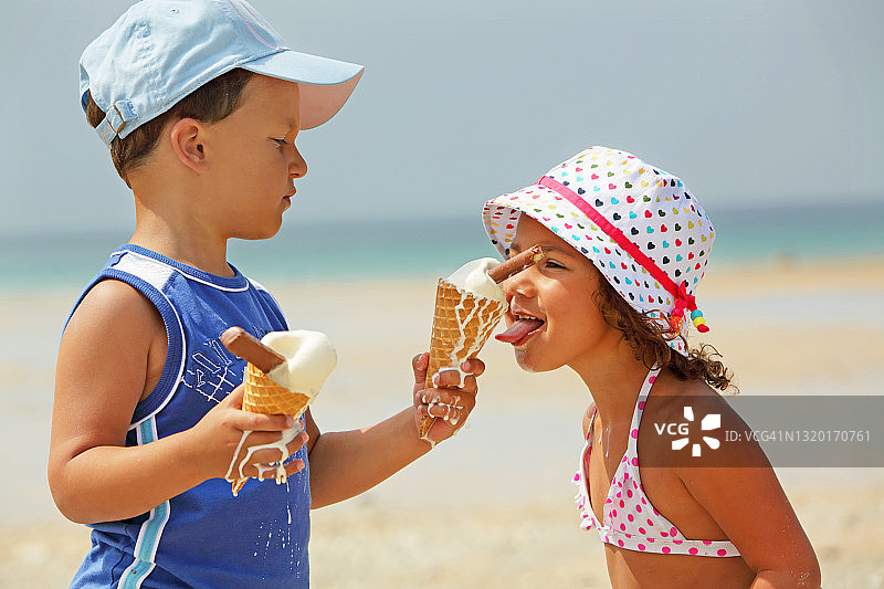 哥哥和妹妹在海滩上吃正在融化的冰淇淋图片素材