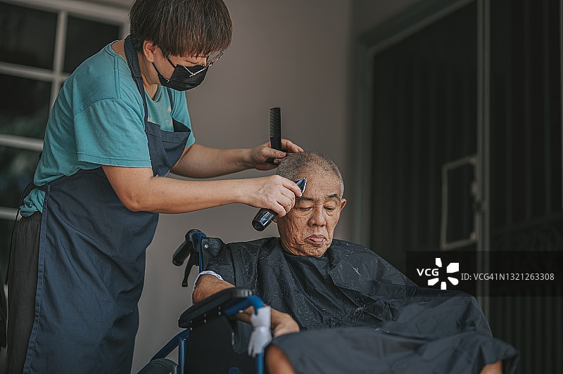坐在轮椅上的华裔老人在自家前院理发图片素材
