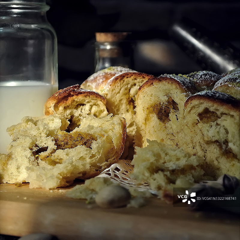 食物摄影的面包屑奶油蛋卷(奶油蛋卷)与开心果馅侧视图。一块撕破的法国糕点奶油蛋卷在黑暗的背景近景。微距摄影图片素材
