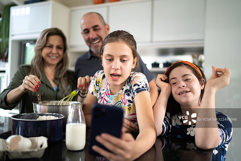 一家人一起做蛋糕，一起在家里使用智能手机——包括一个特殊需要的女孩图片素材