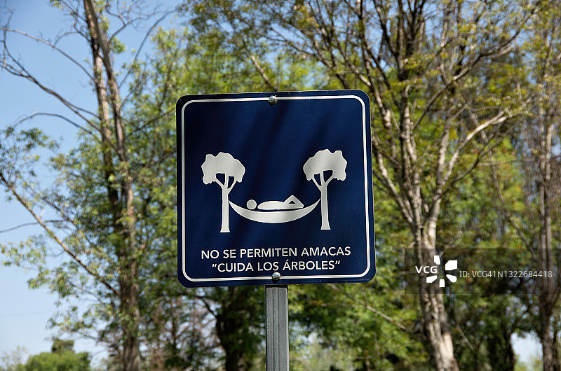 西班牙语标牌上写着“禁止使用吊床”(“爱护树木”)图片素材