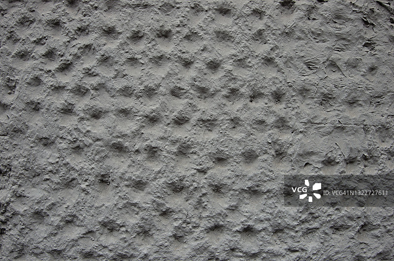 粗糙的混凝土灰泥建筑外部，带有圆形凹痕，漆成米色/浅灰色图片素材
