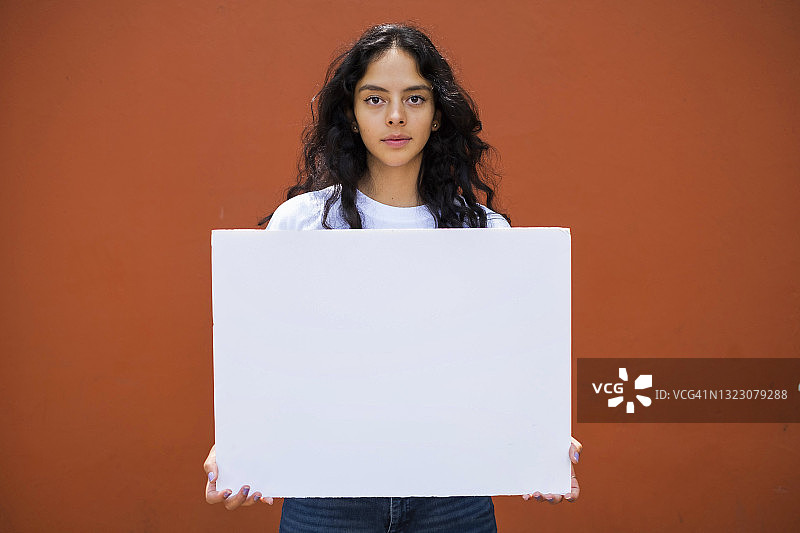 年轻的拉丁裔妇女举着一个空白的牌子图片素材