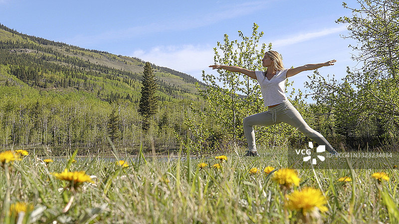 一名年轻女子在花草地上练习瑜伽图片素材