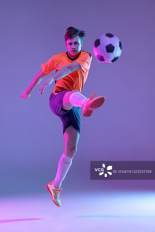 年轻的白人男子，男性足球运动员训练孤立在梯度蓝粉色背景霓虹灯图片素材