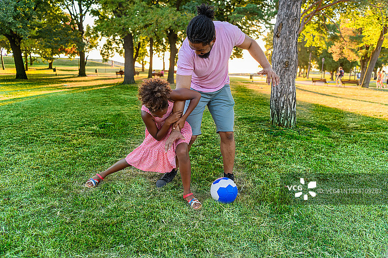 快乐的非洲裔美国家庭在公园里玩足球。图片素材