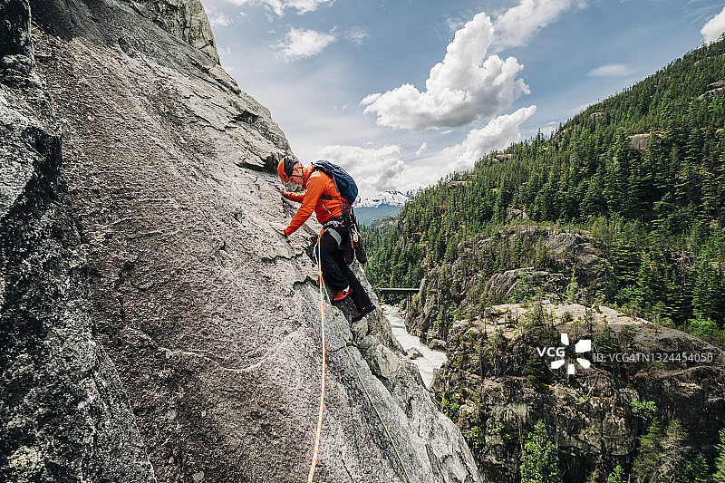 一位男性攀岩者带领着一个岩石面，高于一个山脉河谷附近的惠斯勒，BC图片素材