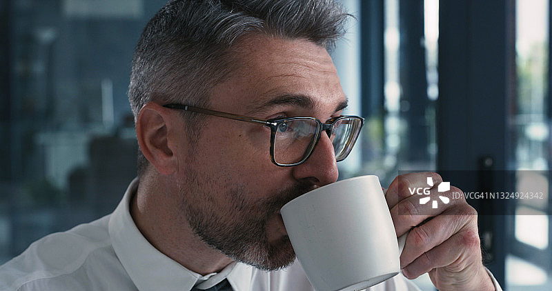 这是一个在办公室喝咖啡的成熟商人的照片图片素材