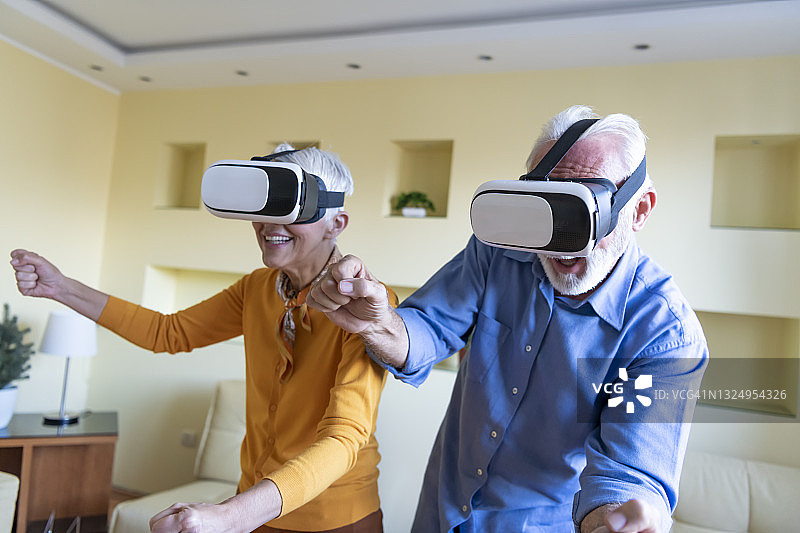 一位老人和他的妻子正在用虚拟现实眼镜浏览一个虚拟世界。图片素材