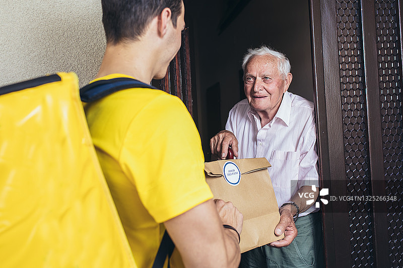 年轻男性志愿者送购物给老人。图片素材