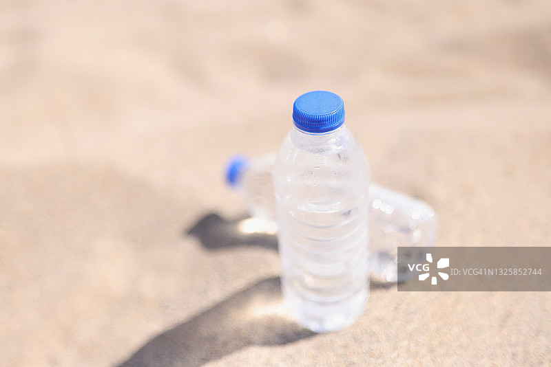 塑料水瓶站在热沙子上特写图片素材