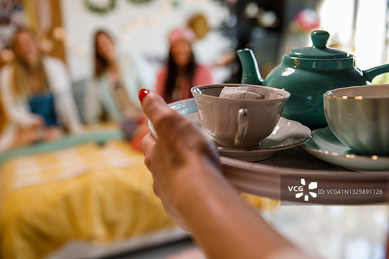 一个女人拿着一个盛着茶的托盘给她的朋友图片素材