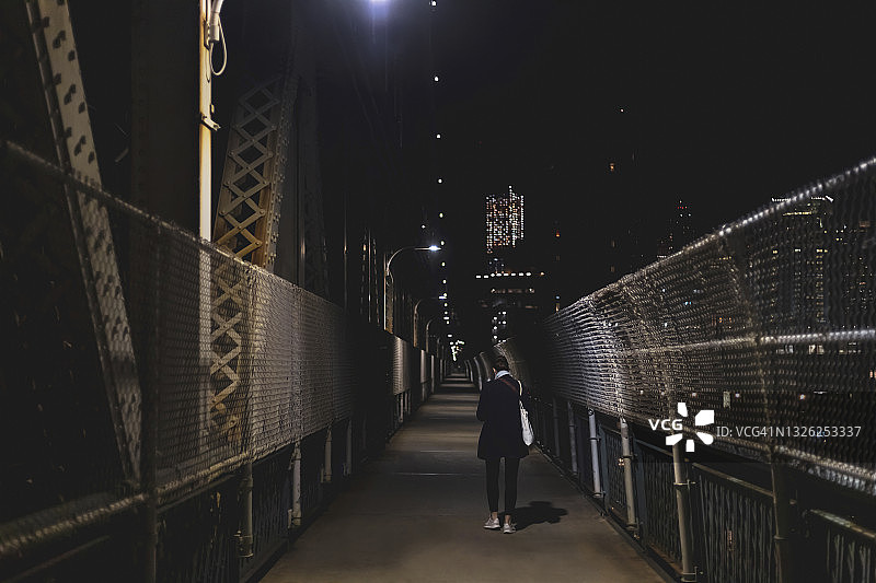 年轻女子在夜里过桥。图片素材