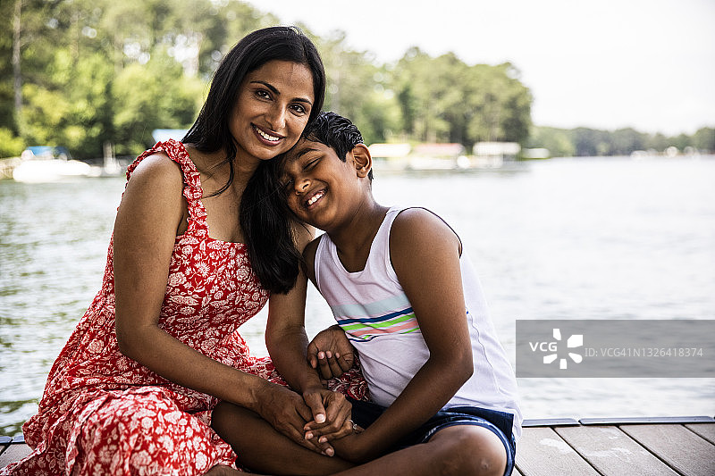 母亲和儿子在湖边的码头上拥抱图片素材