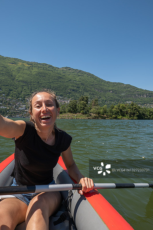 年轻女子在山湖上的红色独木舟上自拍图片素材