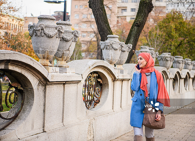 一个美丽的穆斯林妇女戴着头巾走在城市街道上的肖像。图片素材