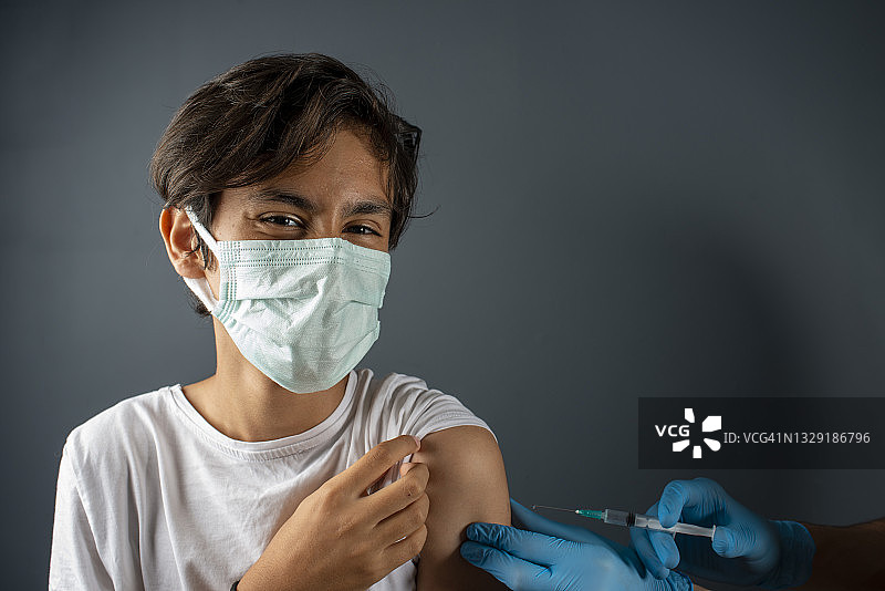 护士为冠状病毒流行的青少年男孩接种疫苗。图片素材
