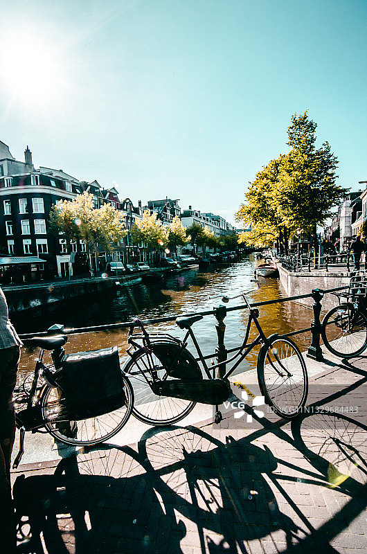阳光明媚的一天，荷兰阿姆斯特丹运河上的自行车图片素材