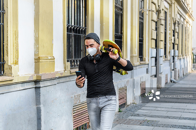 一个年轻人在街上拿着一块长木板，用着电话。图片素材