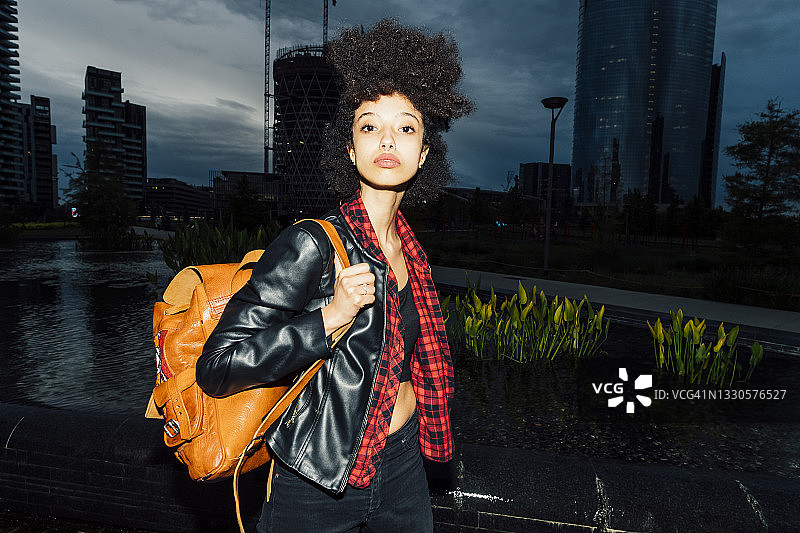 黄昏时分，年轻女子背着背包在城市里图片素材
