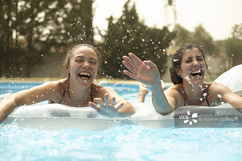 两个美丽的中年妇女享受一个夏天在游泳池充气垫图片素材