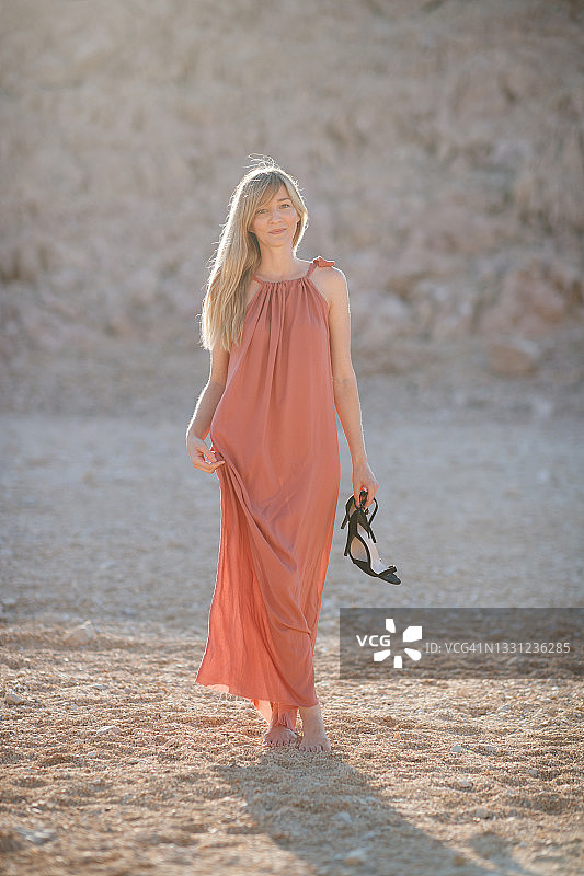 穿着夏装的美女站在石头沙漠里看着镜头图片素材