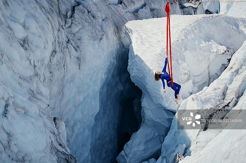 一名女子在冰川裂缝深处的空中吊床上表演动态特技图片素材