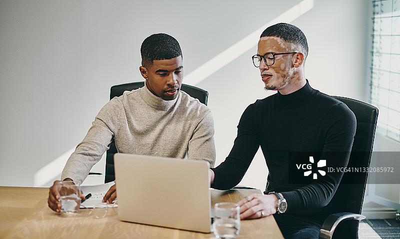 两名年轻的商人在现代办公室开会时使用笔记本电脑图片素材