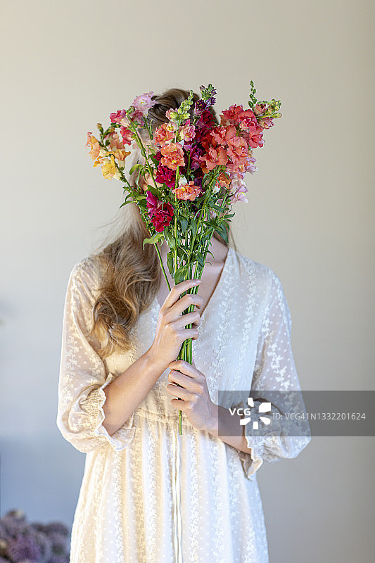 一名年轻女子在画室用花束遮住脸图片素材