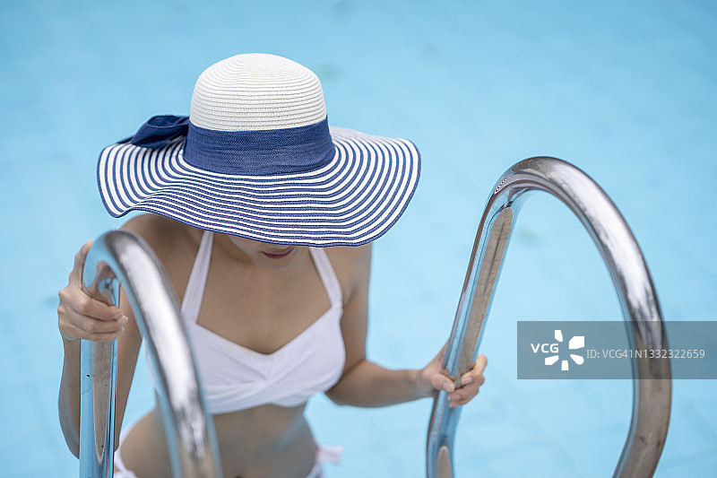 游泳池边的女人戴着太阳帽图片素材