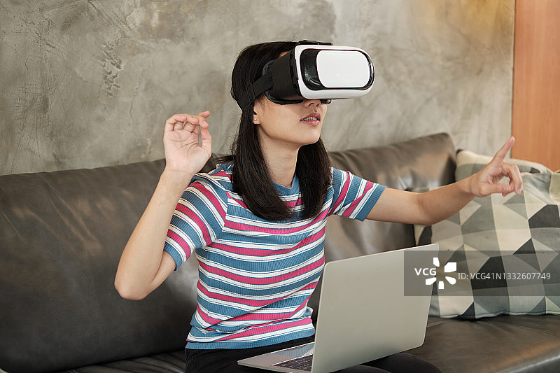 亚洲女性戴着虚拟现实头盔，观看3D虚拟模拟。图片素材