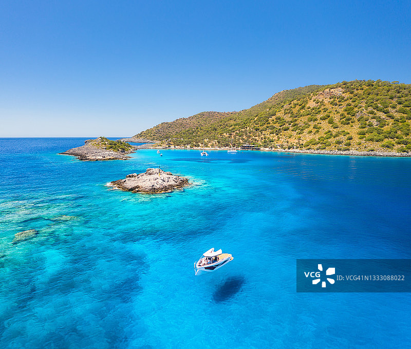 夏日阳光明媚的日子，美丽的游艇在海上的鸟瞰图。Akvaryum koyu在土耳其。俯瞰豪华游艇，泻湖与透明的蓝色水，岩石，天空，山和绿树。旅行图片素材