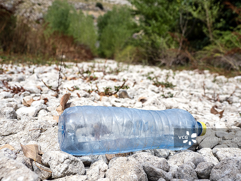 被遗弃在河边的塑料水瓶因天气而干涸。图片素材