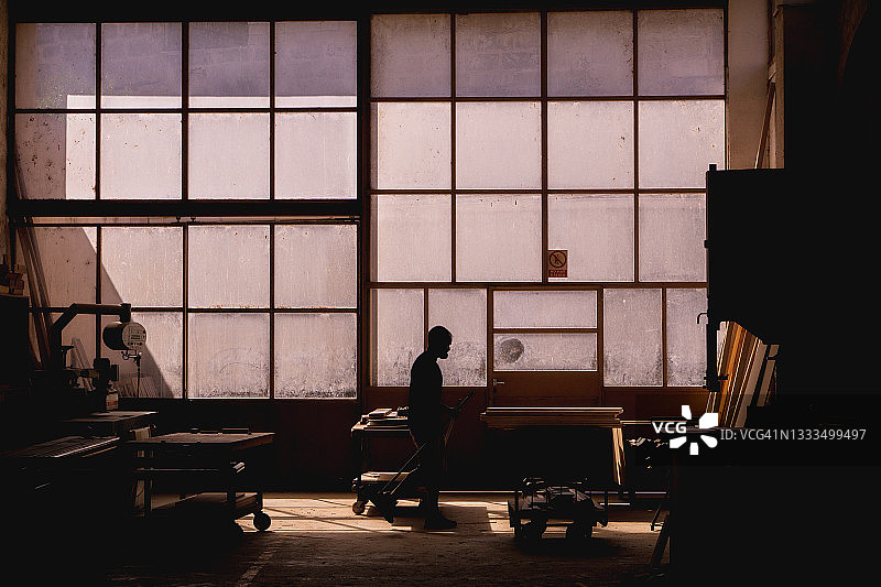 木工车间，工人有窗户背光照明图片素材