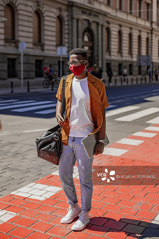 非洲裔美国人自信的年轻人戴着防护口罩穿过街道图片素材