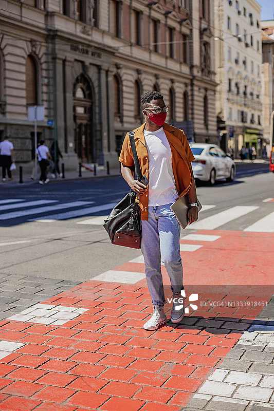 非洲裔美国人自信的年轻人戴着防护口罩穿过街道图片素材