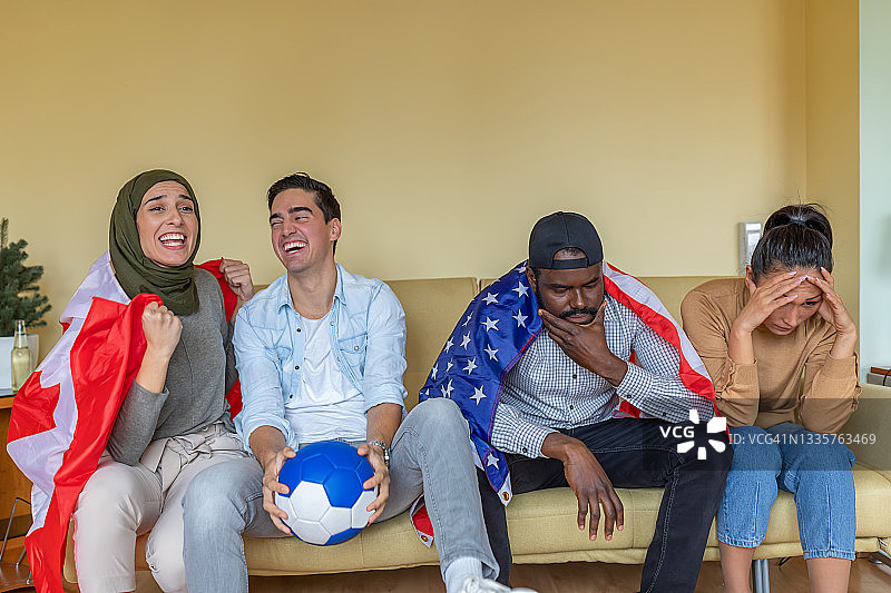 快乐的一群年轻的美国和加拿大朋友在一起度过美好的时光，在家里看足球比赛。图片素材