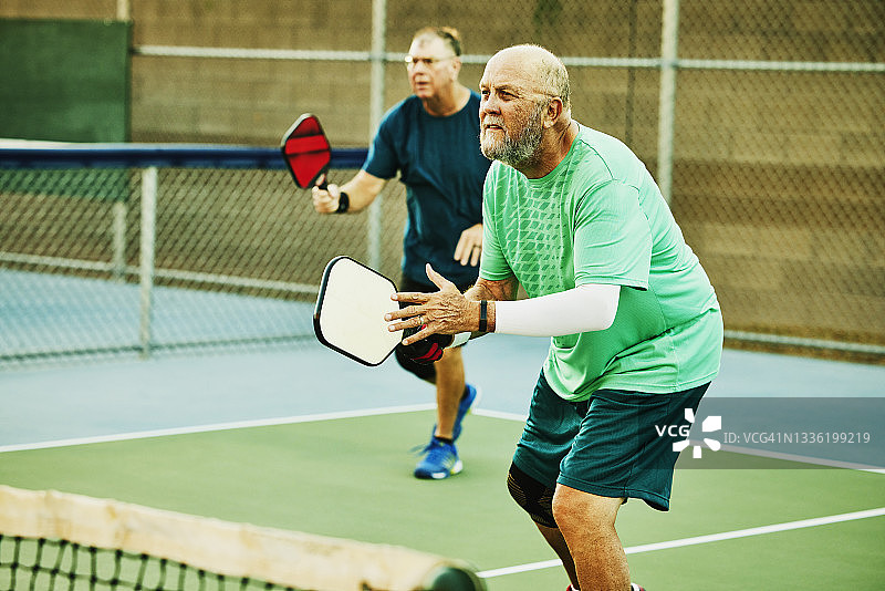 在双打匹克球比赛中，老男子打网球的宽镜头图片素材